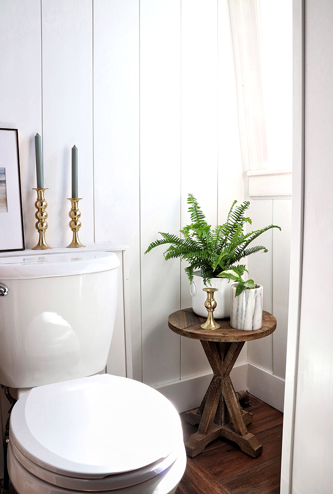 toilet in white bathroom gold candlesticks green plant