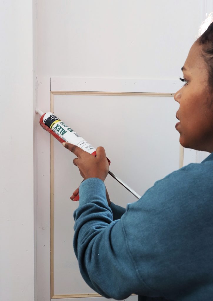 woman caulking wall